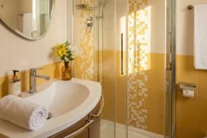 Don Milani: bagno con piastrelle gialle, lavabo e box doccia