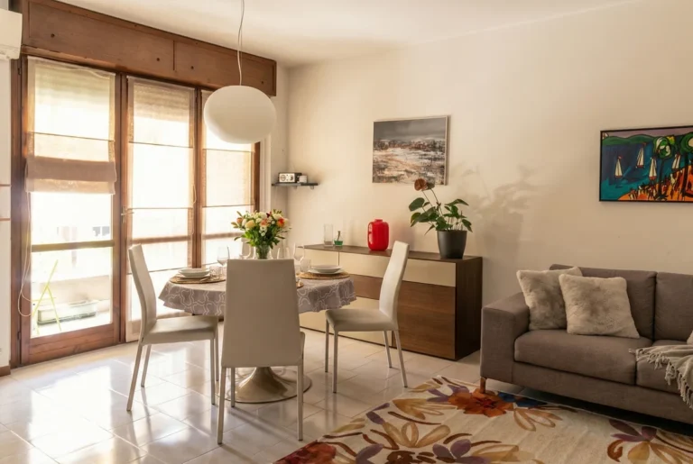 Don Milani: soggiorno con tavolo da pranzo, divano e ampie finestre luminose